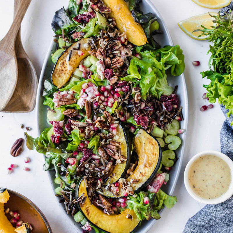 Fall Harvest salad set on glass plate on nice tablecloth surrounded by greens and dressing