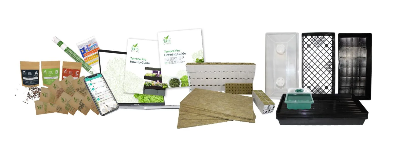 Various Les Verts Terrace Pro accessories including a pH meter, seed packets and fertilizer packets, in front of a laptop and phone and Growing Guides